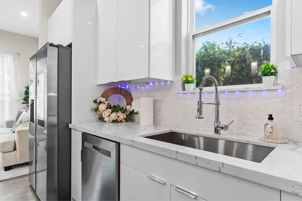 a kitchen with stainless steel appliances a sink a refrigerator and a window