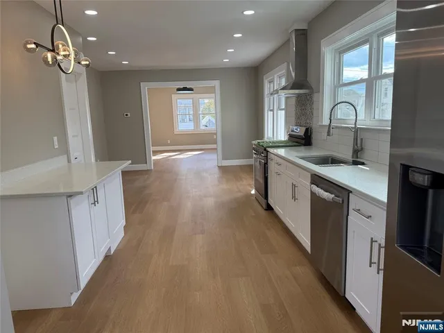 a large kitchen with stainless steel appliances granite countertop a lot of counter space and wooden floor