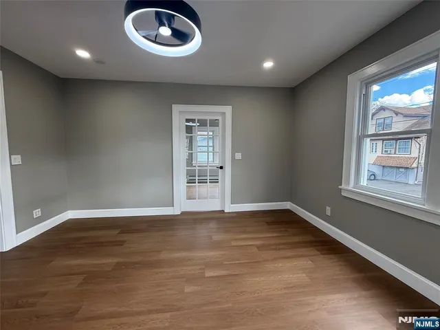 a view of an empty room with a window and wooden floor