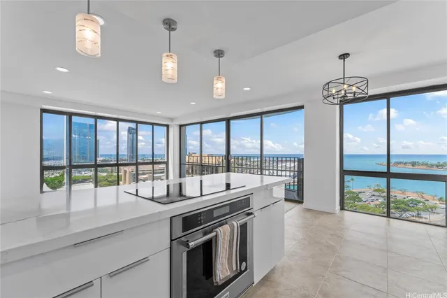 a dining hall with stainless steel appliances granite countertop a stove and a view of living room