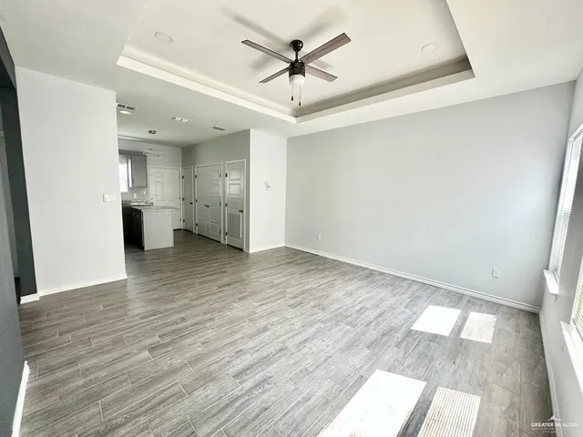a view of empty room with wooden floor and ceiling fan