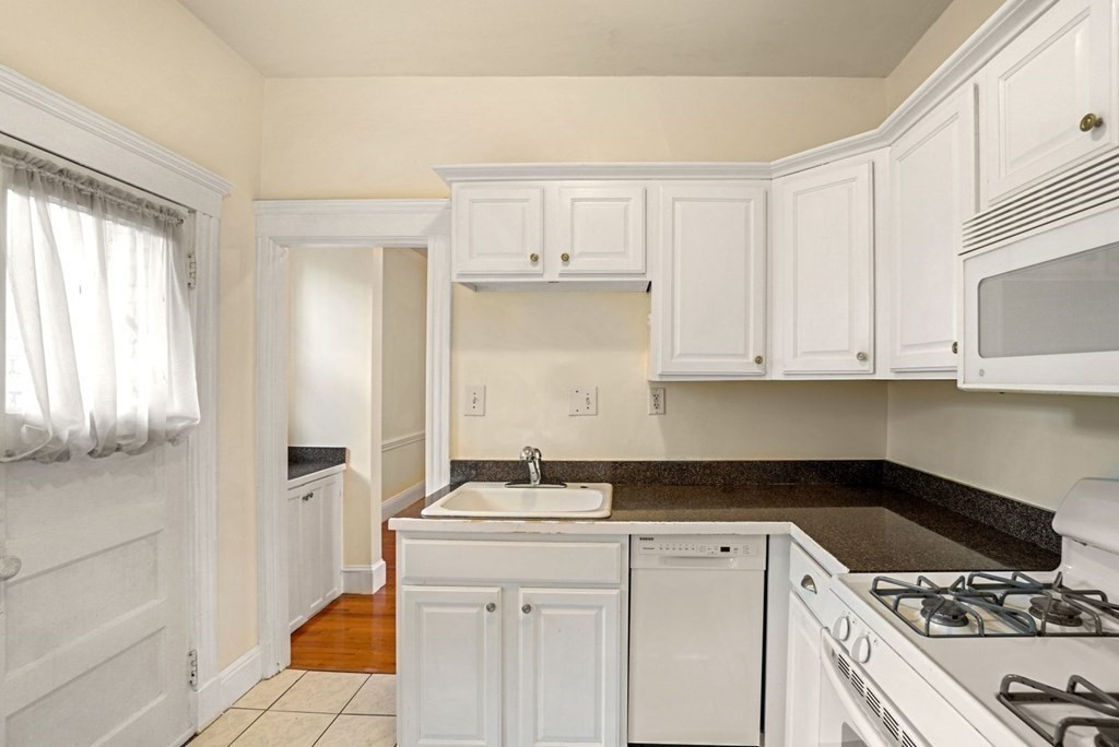 55 Lanark Road, Unit 6 Boston, MA 02135 - Photo 2 of 12 a kitchen with granite countertop a sink a stove and cabinets