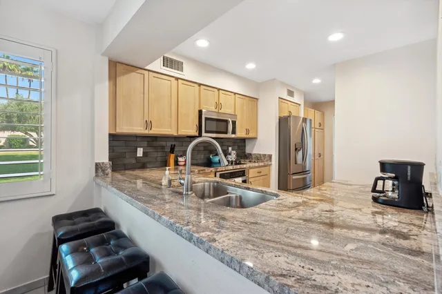 a kitchen with kitchen island granite countertop a stove refrigerator and cabinets