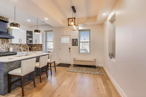 a view of a kitchen with kitchen island stainless steel appliances wooden floor dining table and chairs