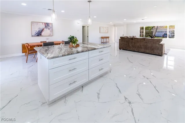 a large white kitchen with stainless steel appliances kitchen island granite countertop a sink and a refrigerator