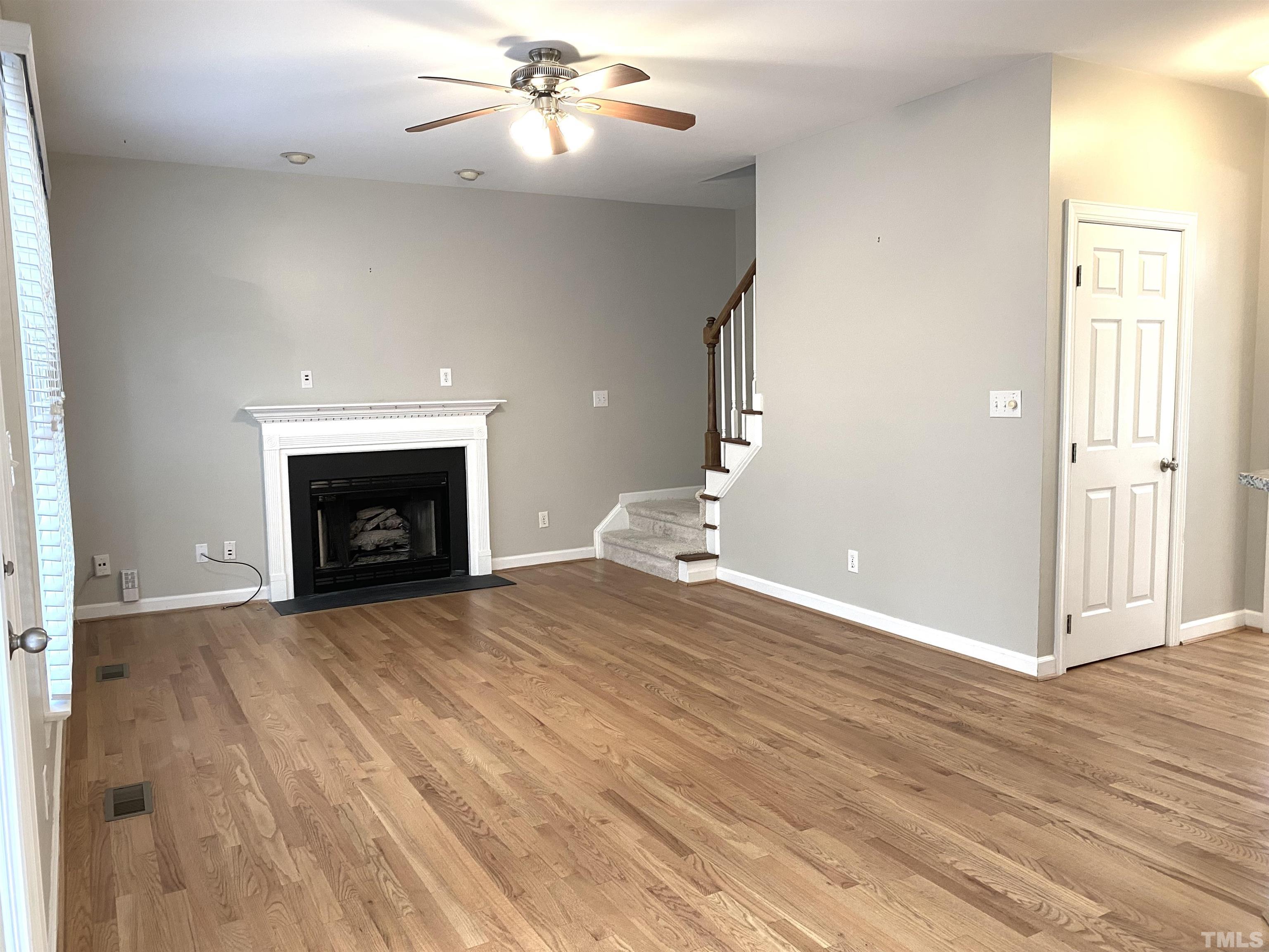 4313 Fowler Ridge Drive Raleigh, NC 27616 - Photo 9 of 30 an empty room with wooden floor fireplace and windows
