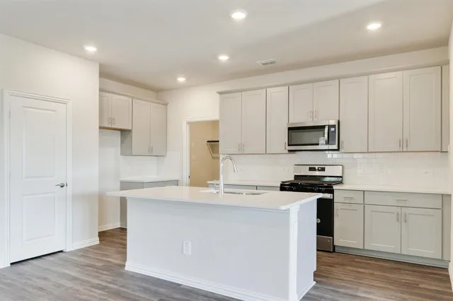 a kitchen with stainless steel appliances a white stove top oven and white cabinets