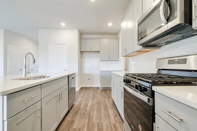 a kitchen with wooden floor a sink a stove and a refrigerator