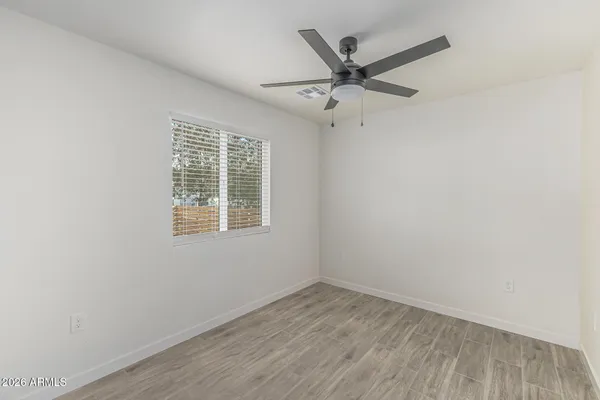 an empty room with wooden floor fan and windows