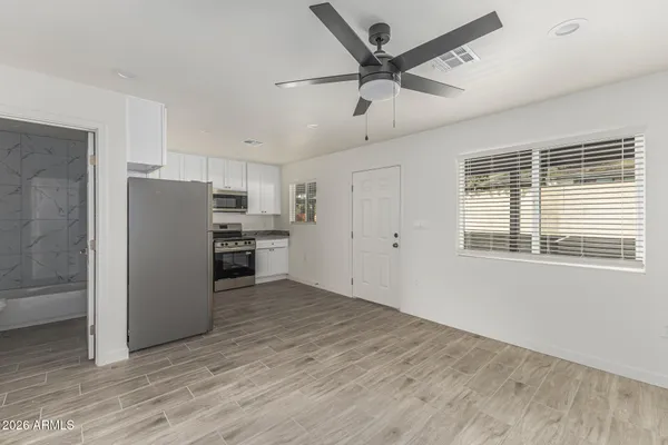 a view of a kitchen with a refrigerator a ceiling fan and wooden floor