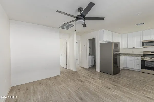 a view of a kitchen with a refrigerator a ceiling fan and wooden floor
