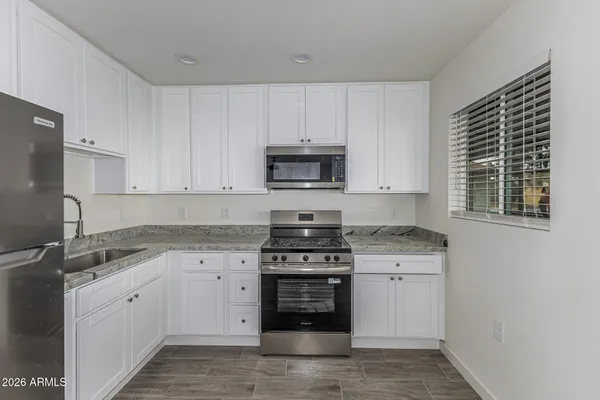 a kitchen with granite countertop white cabinets and stainless steel appliances