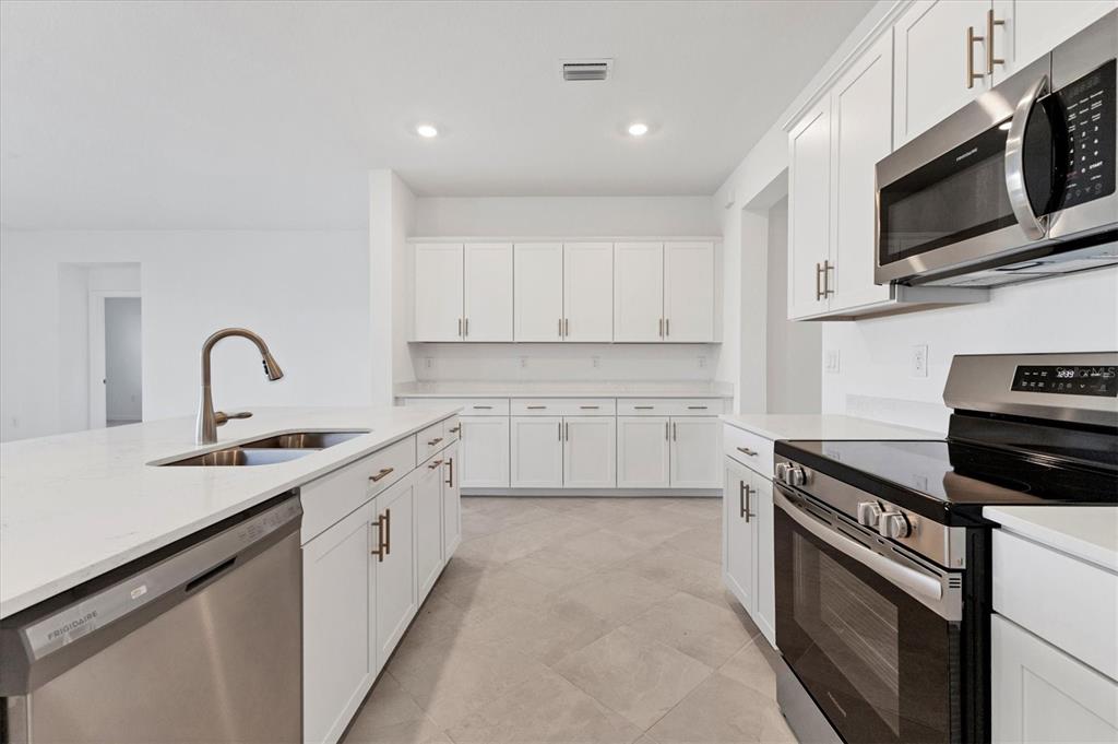 19095 Cabernet Court Venice, FL 34293 - Photo 9 of 76 a kitchen with stainless steel appliances granite countertop a sink dishwasher stove and microwave with wooden cabinets