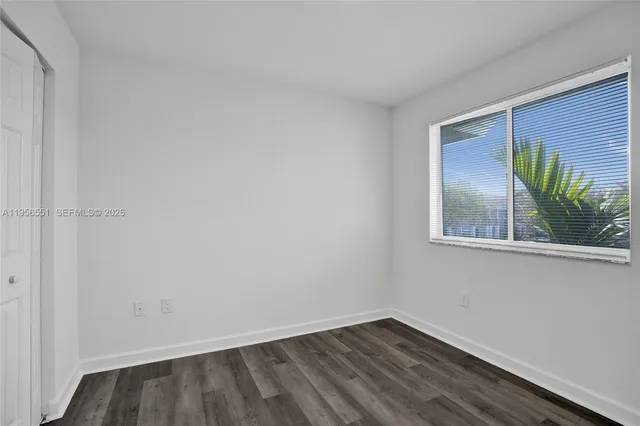 a view of an empty room with window and wooden floor