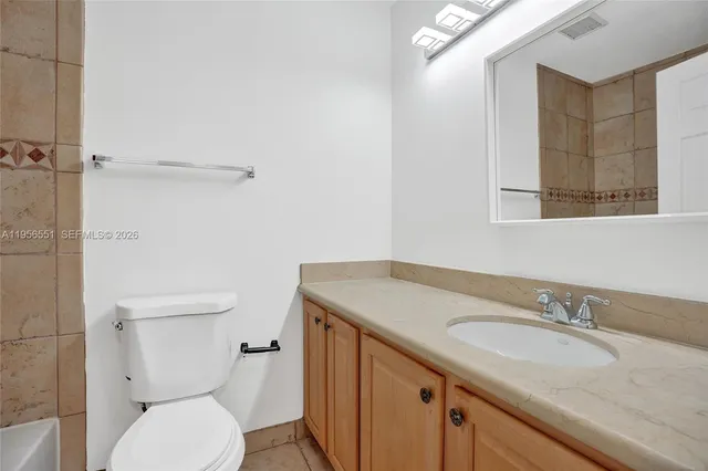 a bathroom with a granite countertop sink a toilet and a mirror