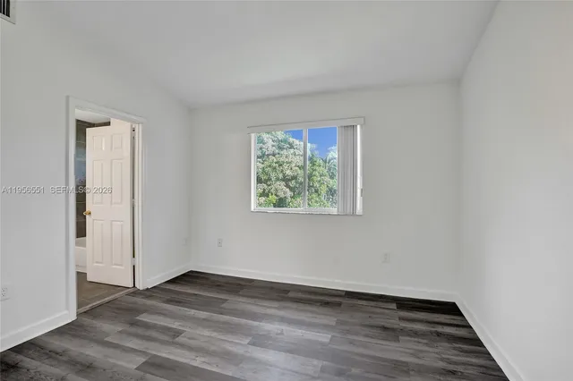 an empty room with wooden floor closet and windows