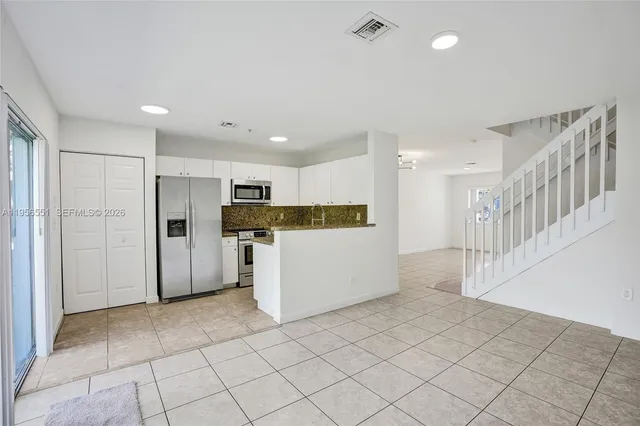 a view of a kitchen with refrigerator and white cabinets