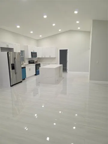 a view of kitchen with stainless steel appliances a refrigerator counter top oven and a sink