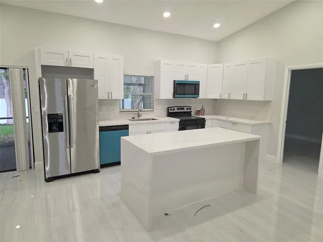 a kitchen with a refrigerator a stove top oven a sink and cabinets