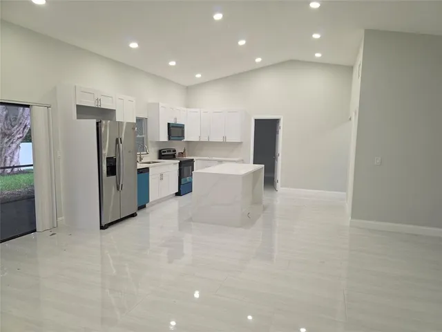 a large kitchen with stainless steel appliances a refrigerator and a stove top oven