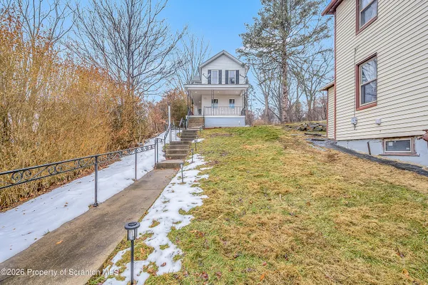 a view of a house with a large tree and wooden fence