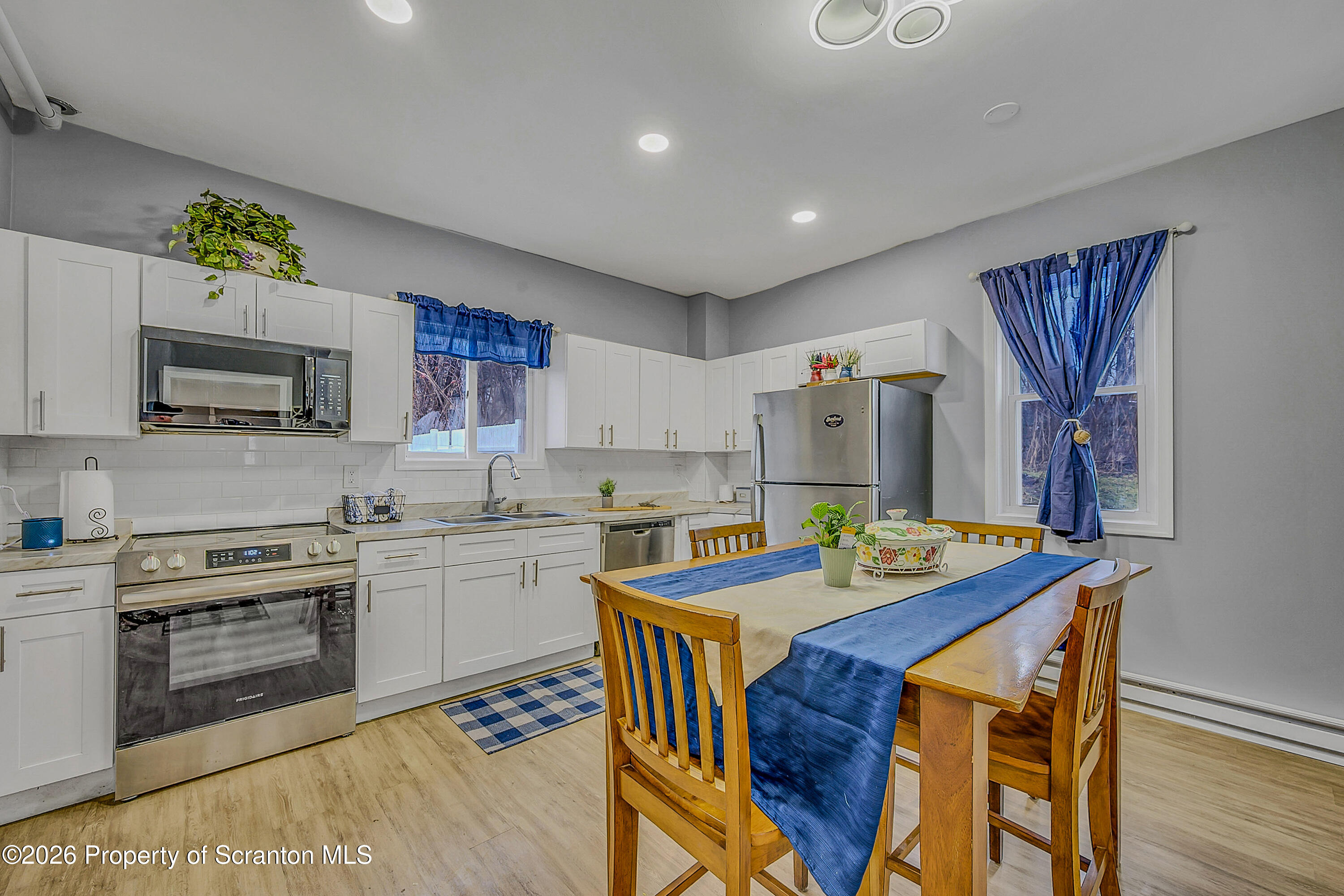 215 North Fillmore Avenue Scranton, PA 18504 - Photo 9 of 25 a kitchen with a stove a sink a microwave a dining table and chairs