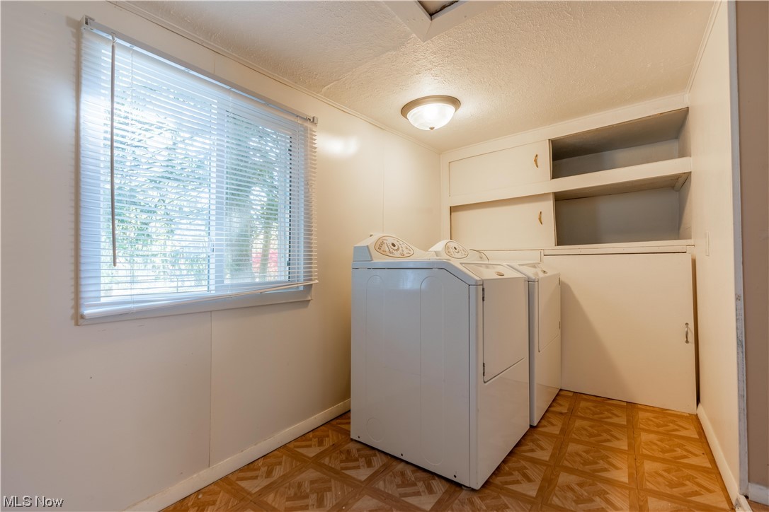 337 Yager Road Clinton, OH 44216 - Photo 11 of 34 Clothes washing area with washing machine and clothes dryer, a textured ceiling, and light parquet floors