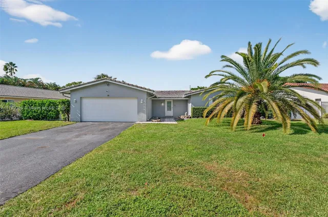 a view of a house with a yard and palm trees