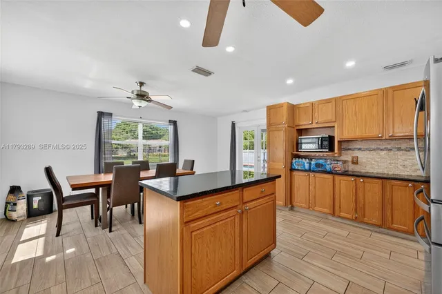 a kitchen with stainless steel appliances granite countertop a sink a stove top oven a refrigerator with island and chairs