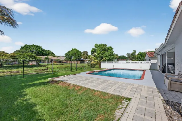 a view of backyard with swimming pool and seating space