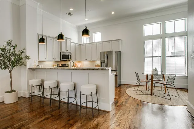 a kitchen with stainless steel appliances granite countertop a stove a refrigerator a kitchen island a table and chairs with wooden floor