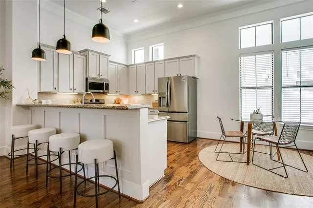 a kitchen with stainless steel appliances a dining table chairs refrigerator and microwave
