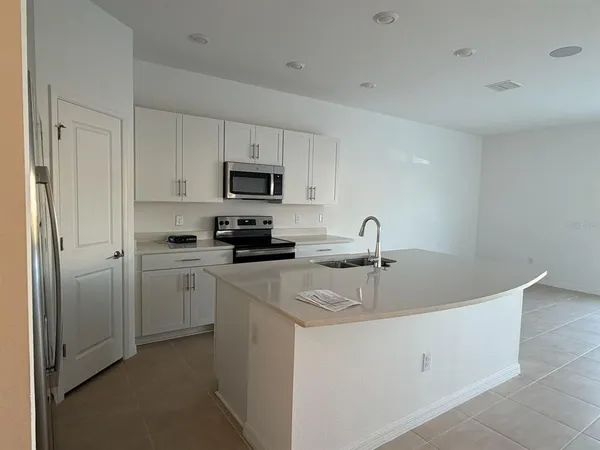 a kitchen with white cabinets a sink and appliances