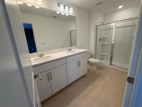 a bathroom with a double vanity sink toilet and shower