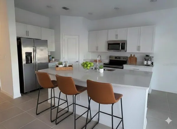 a kitchen with stainless steel appliances a dining table chairs refrigerator and sink