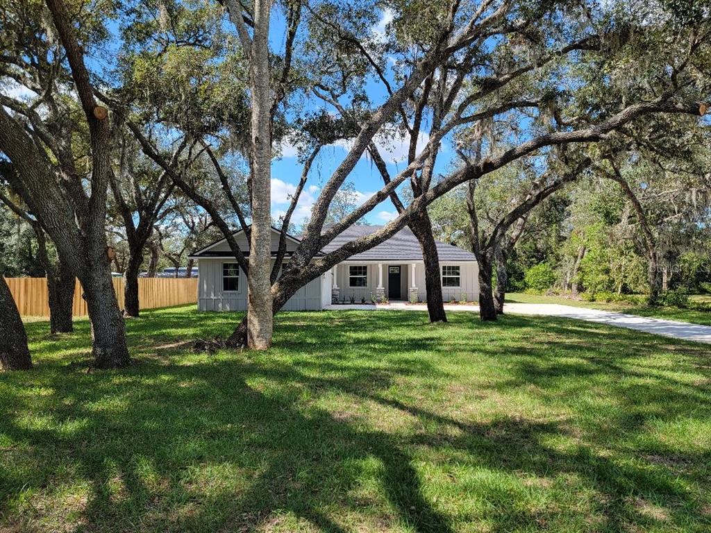 2115 Capps Road Lake Wales, FL 33898 - Photo 1 of 1 a white house in a big yard with large trees
