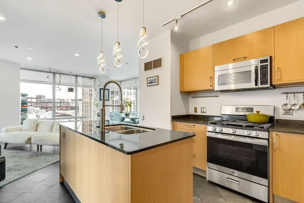 a kitchen with stainless steel appliances granite countertop a stove a sink and a microwave