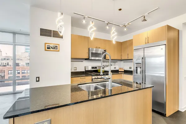 a kitchen with stainless steel appliances granite countertop a refrigerator a stove and a sink with wooden floor