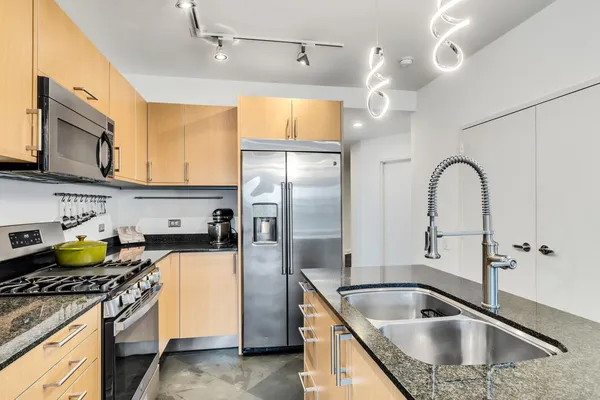 a kitchen with stainless steel appliances granite countertop a sink a stove and refrigerator