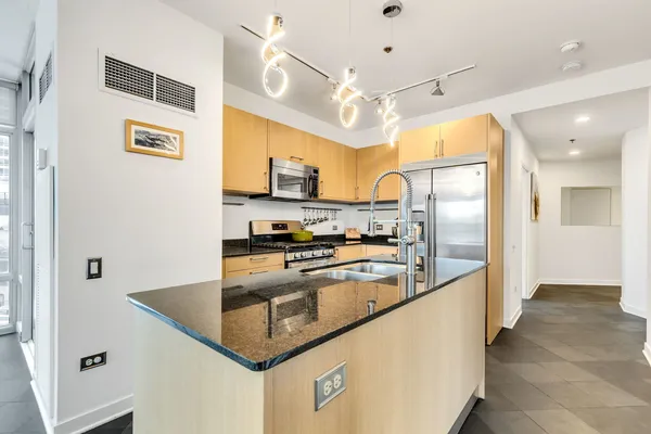 a kitchen with stainless steel appliances granite countertop a refrigerator a sink and a stove