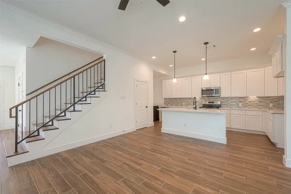 a large white kitchen with wooden floors stainless steel appliances and white cabinets