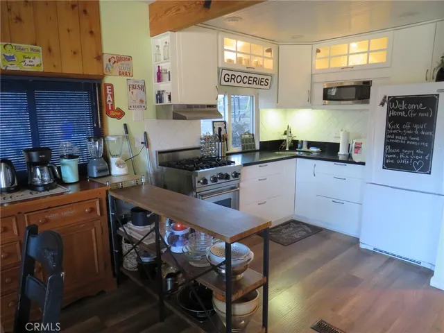 a kitchen with stainless steel appliances granite countertop a stove a sink dishwasher and cabinets with wooden floor