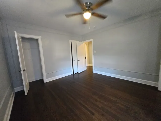 an empty room with wooden floor and ceiling fan