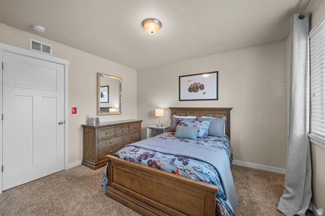 955 Delorean Lane Midvale, UT 84047 - Photo 27 of 47 Bedroom featuring neutral wall paint, textured carpet flooring, a white interior door, and a window with horizontal blinds