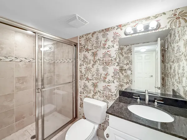 a bathroom with a granite countertop sink toilet a mirror and shower