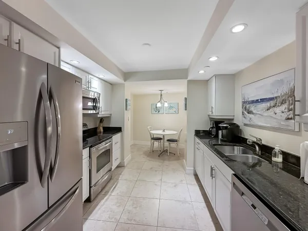 a large kitchen with stainless steel appliances granite countertop a sink stove and refrigerator