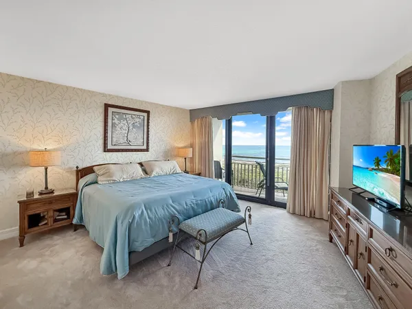 a spacious bedroom with a bed and a flat tv screen on the dresser