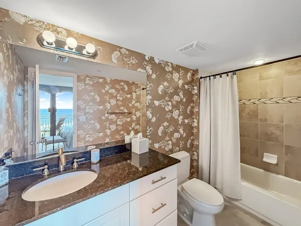 a bathroom with a granite countertop sink a toilet a mirror a vanity and shower