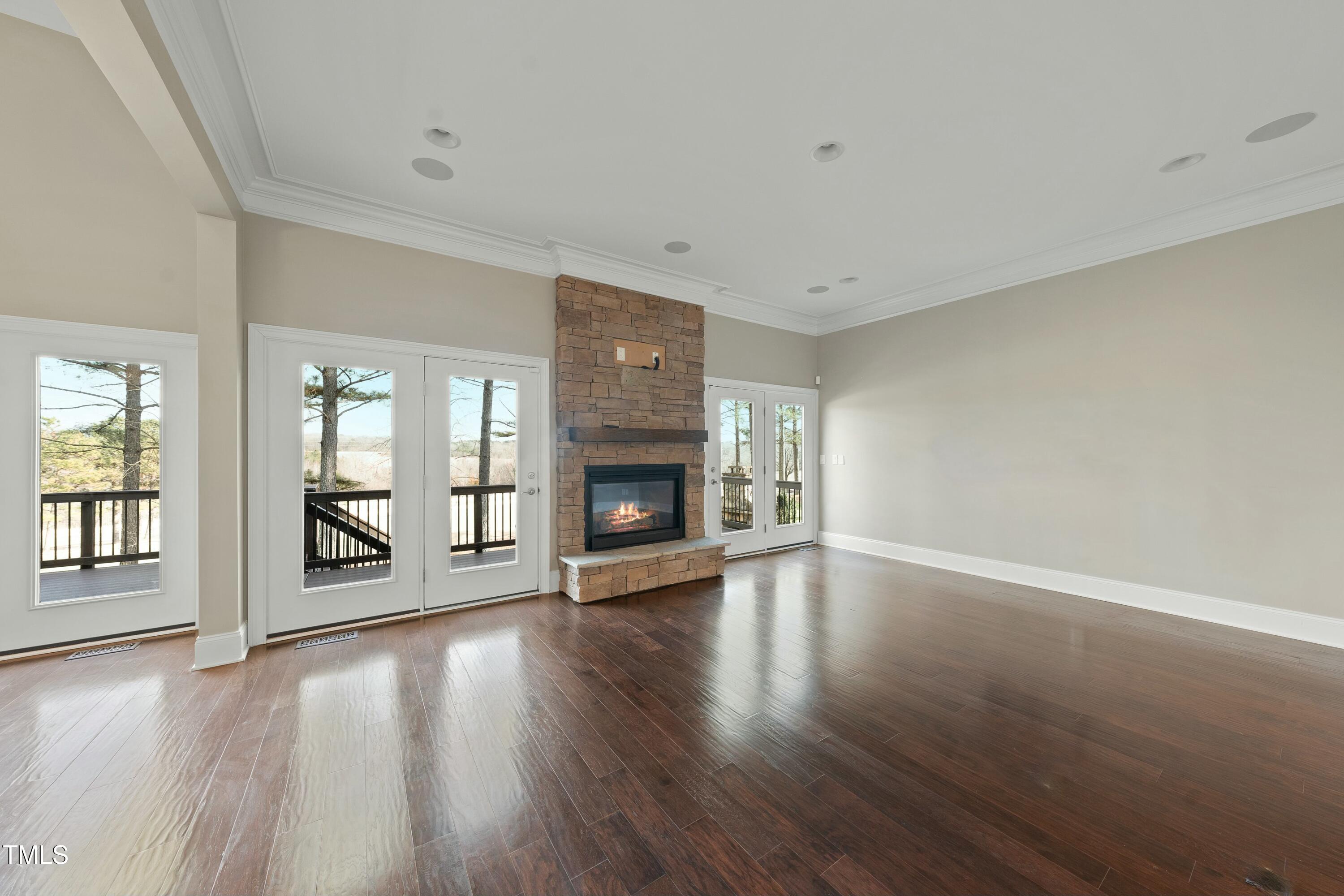 7220 Hasentree Way Wake Forest, NC 27587 - Photo 9 of 39 an empty room with wooden floor fireplace and windows