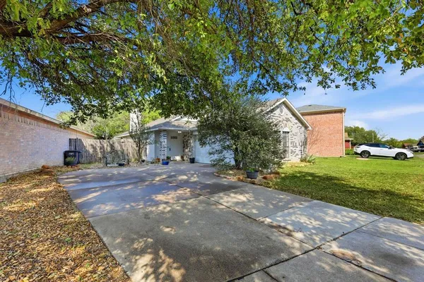a view of a house with a yard and large tree